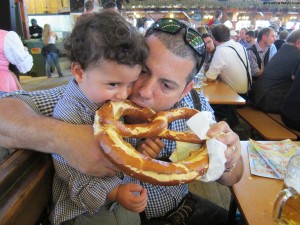 a man kissing a child's face while eating a pretzel