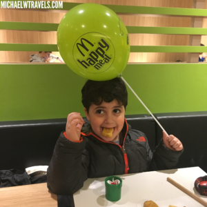 a boy sitting at a table with a balloon on his head