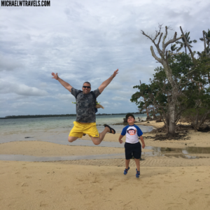 a man and boy jumping in the air on a beach