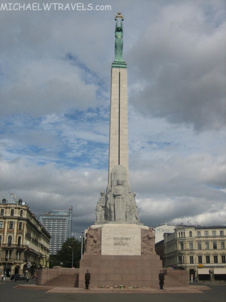 a tall monument with a statue on top with Freedom Monument in the background