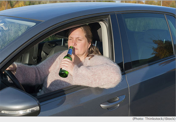 a woman drinking a beer while driving