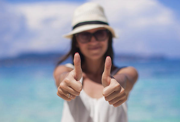 a woman wearing a hat and sunglasses giving thumbs up