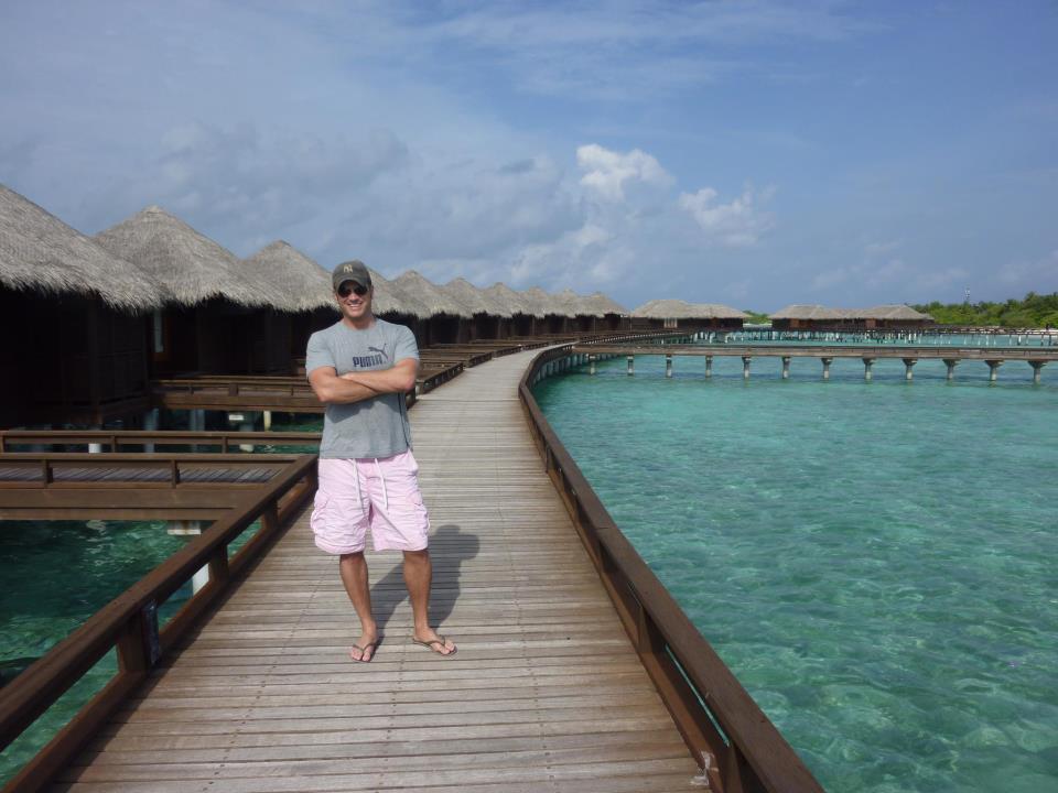 a man standing on a dock with a hut and huts on the water