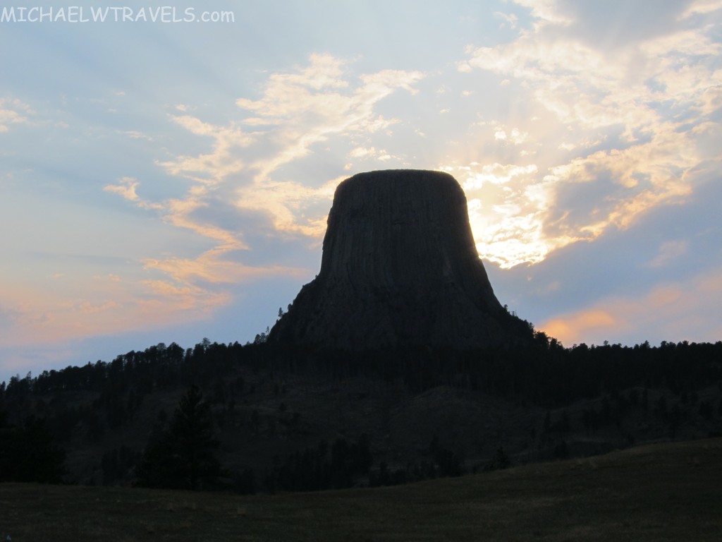 a large rock formation on a hill with Devils Tower in the background