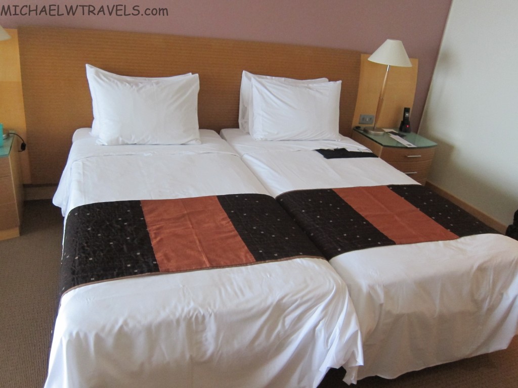 a bed with white sheets and brown and black blankets