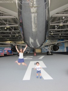 a woman and child jumping in front of an airplane