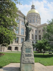 a statue of a woman holding a torch in front of Georgia State Capitol