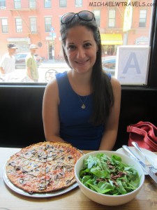 a woman sitting at a table with a pizza and salad