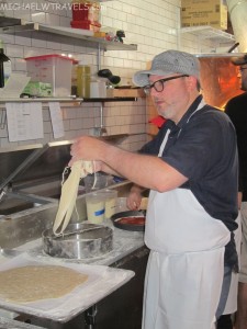 a man making pizza in a kitchen