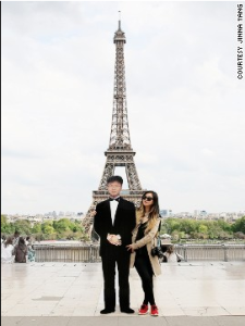 a man and woman posing for a picture in front of a tall tower
