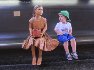 a boy sitting next to a statue of a girl