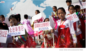 a group of young girls in traditional dress holding signs