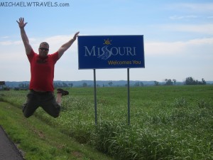 a man jumping in the air in front of a welcome sign