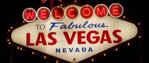 a sign with red and blue text with Welcome to Fabulous Las Vegas sign in the background