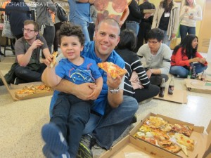 a man holding a child while eating pizza