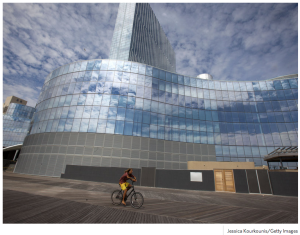 a man riding a bicycle in front of a glass building