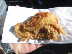 a hand holding a piece of fried chicken