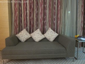 a couch with pillows in front of a curtain
