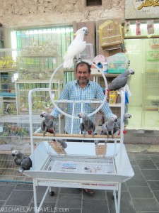 a man standing in front of a cage with birds
