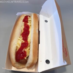 a hot dog with ketchup and cheese in a cardboard box