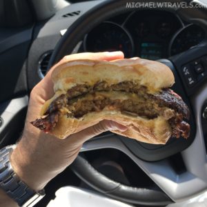 a hand holding a burger in a car