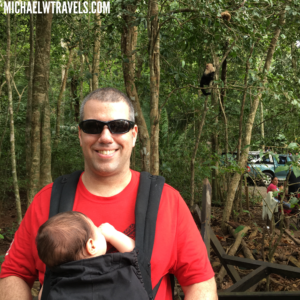a man wearing sunglasses and a baby in a sling