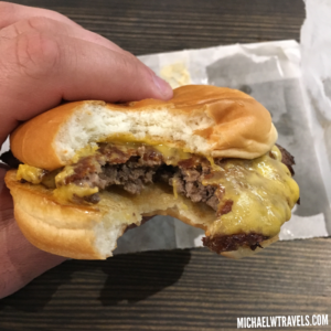 a hand holding a burger with a bite taken out of it