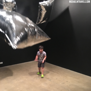 a boy standing in a room with silver pillows