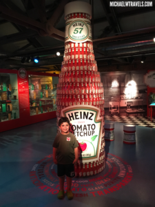 a boy standing in front of a tall bottle tower