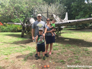 a family posing in front of an old airplane