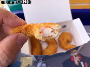a hand holding a fried shrimp