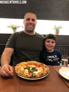 a man and boy sitting at a table with a pizza