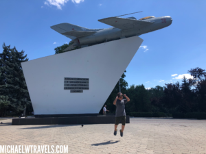 a man jumping in front of a statue of a plane