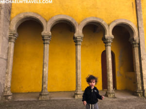 a child standing in front of a yellow building