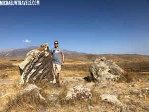 a man standing next to a rock