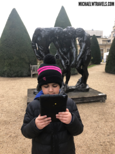a child holding a tablet in front of a statue