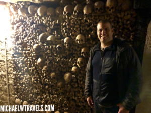 a man standing in front of a wall of skulls