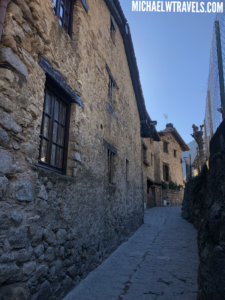a stone alleyway with buildings and a fence