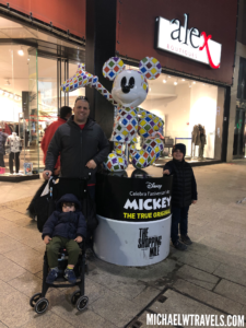 a man and two children posing with a large mickey mouse character