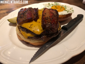 a burger with bacon and eggs on a plate