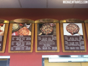 a menu board with pizzas on it