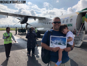 a man holding a child in front of an airplane