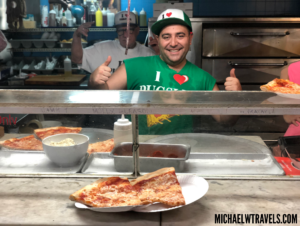 a man behind a counter with pizza