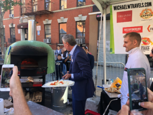 a man in a suit standing in front of a pizza oven