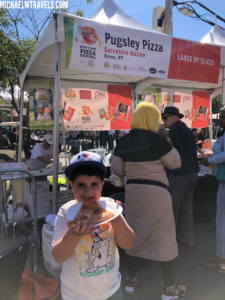 a boy eating pizza at an outdoor event