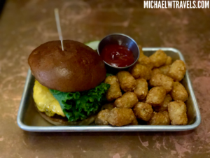 a plate of food with a burger and tater tots