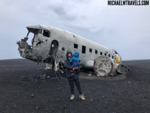 a woman and child standing in front of an airplane wreck