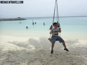 a boy on a swing on a beach