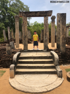 a boy standing in front of a stone structure