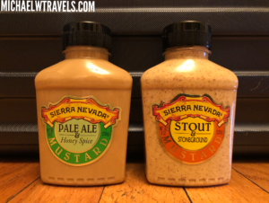 two bottles of mustard on a wood surface